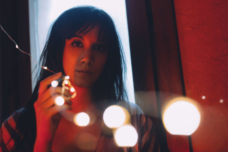 Serious young woman looking through the colored lights