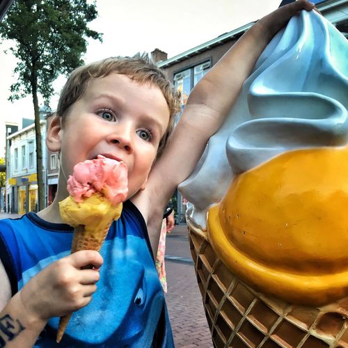 Boy eating ice cream on footpath