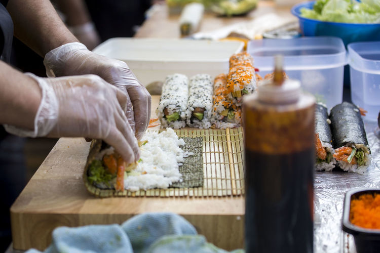 Midsection of person preparing sushi on table