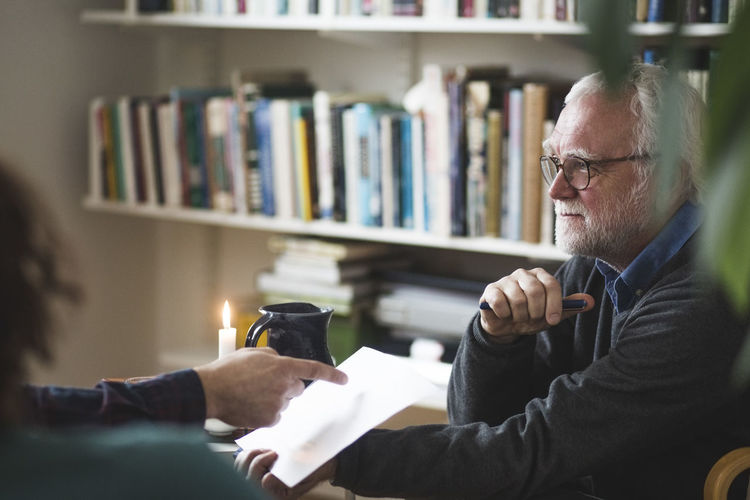 Therapist discussing over document with mature couple at home office