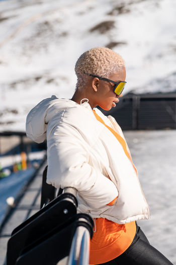 Una mujer afroamericana con gafas de pie en una montaña nevada durante el invierno