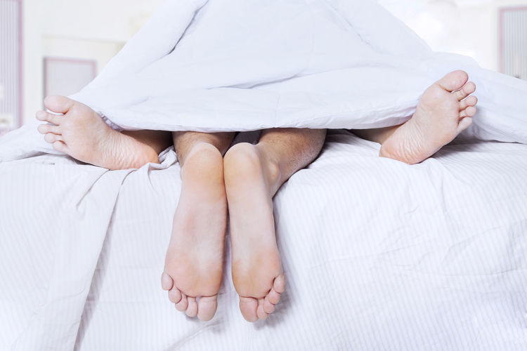 Low section of couple lying on bed