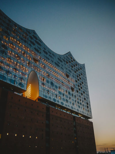 Low angle view of illuminated building against clear sky at dusk
