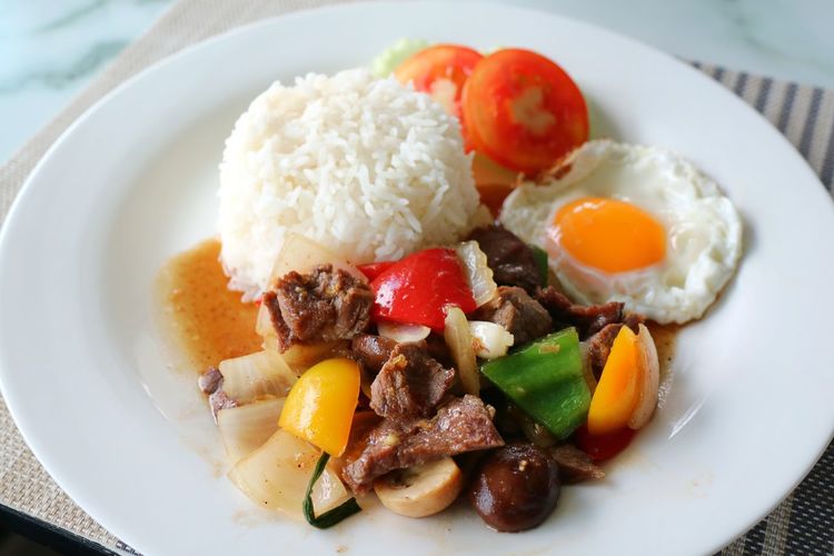 Fried beef with oyster sauce and fried egg on white plate. thai style food concept.