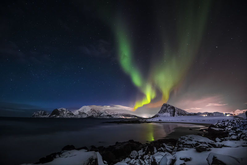 Scenic view of sea and mountains against sky at night