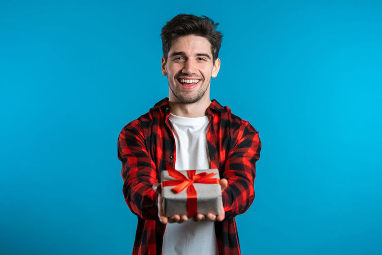 Portrait of smiling young man against blue background