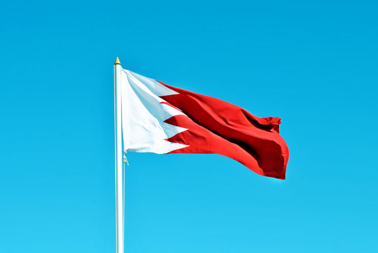 Low angle view of flag waving against clear blue sky