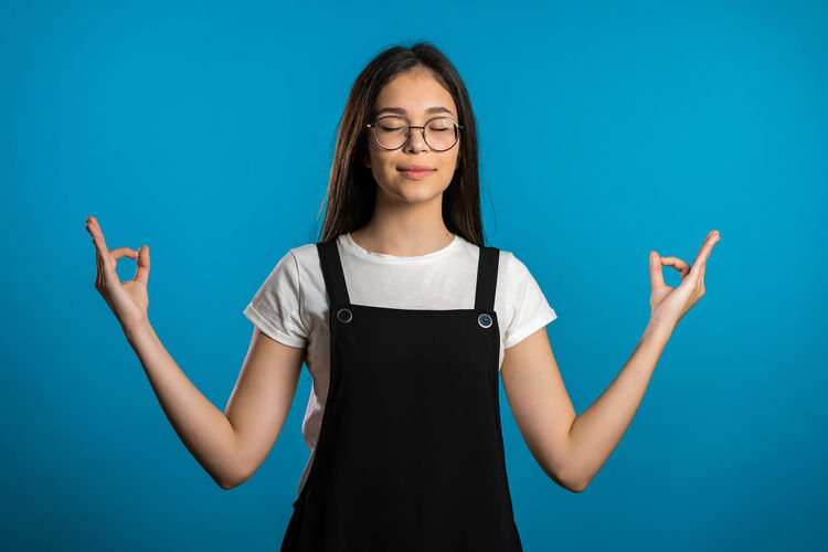 Portrait of teenage girl standing against blue background