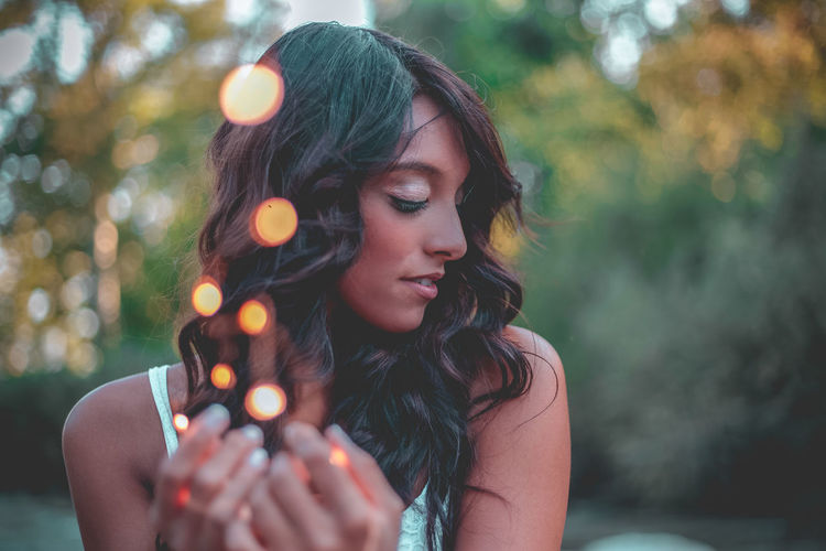Close-up of young woman holding illuminated string light