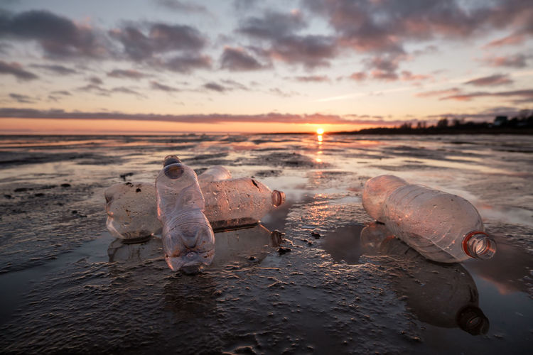 Close-up of plastic bottles thrown on the shore in the backlight