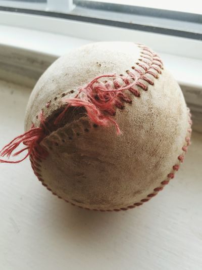 Close-up of damaged baseball ball on window sill