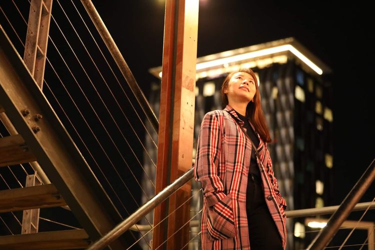 Low angle view of young woman looking away outdoors in the city nightlife