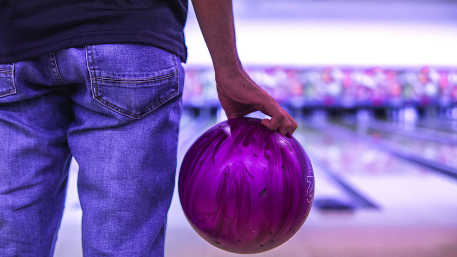 Midsection of man playing ten pin bowling