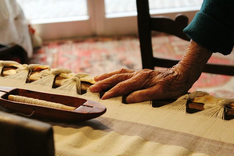 Cropped image of senior woman on weaving machine at workshop