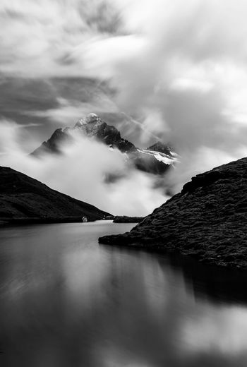 Lake amidst mountains during foggy weather