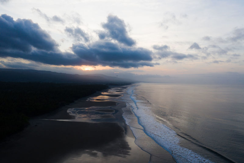 Aerial view of beach during sunrise against mountains