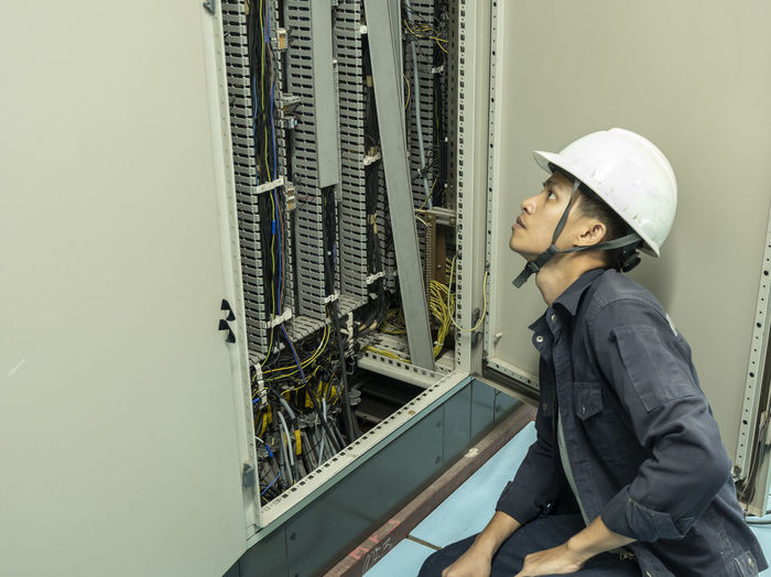 Side view of man working by fuse box