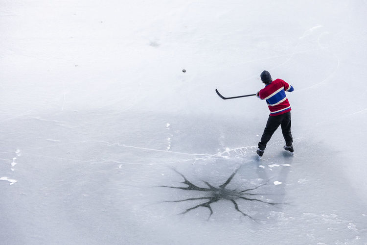 From above unrecognizable hockey player shooting puck on ice in canada