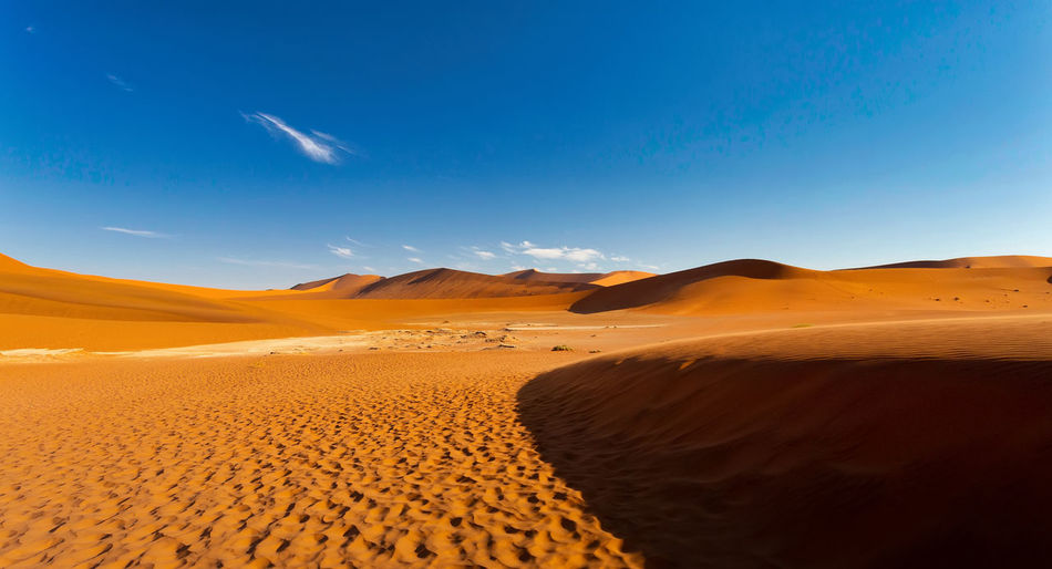 Sand dunes in desert against blue sky