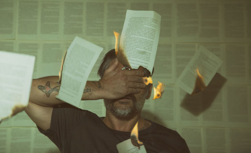 Conceptual image man covering his eyes with his hand and burning a paper bag