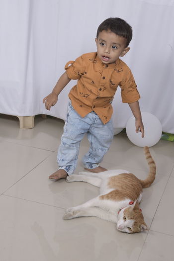 Portrait of a boy with cat on floor at home