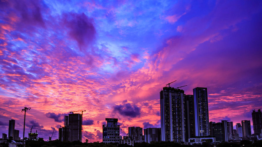 Modern buildings against sky during sunset