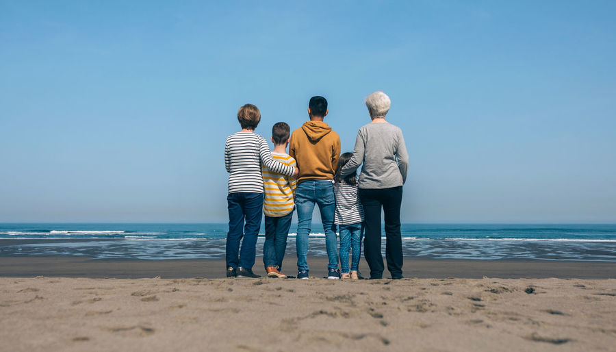 Rear view of family standing at beach