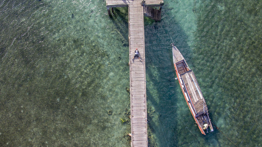 Aerial view of man lying on pier in sea