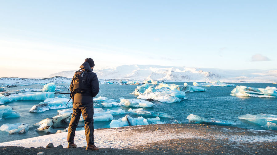 Rear view of man looking at ice bergs on sea
