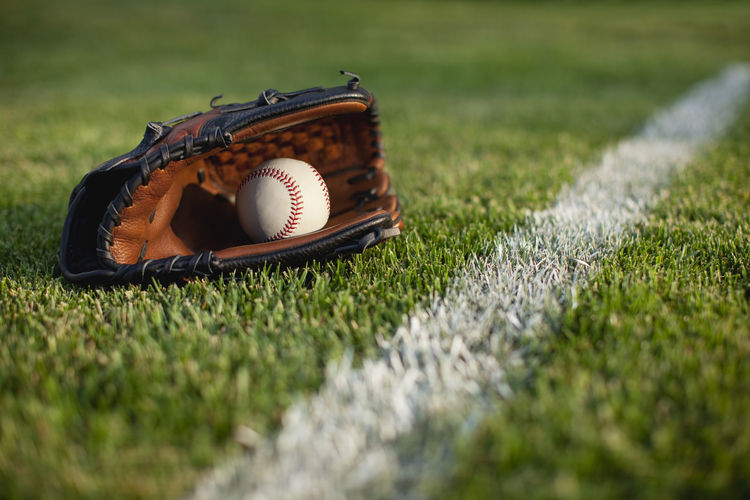 Close-up baseball ball and glove on grass