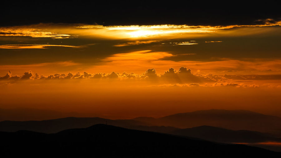 Scenic view of silhouette mountain against dramatic sky during sunset