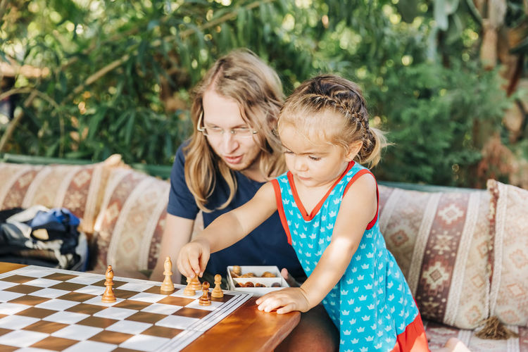Girl playing chess with father