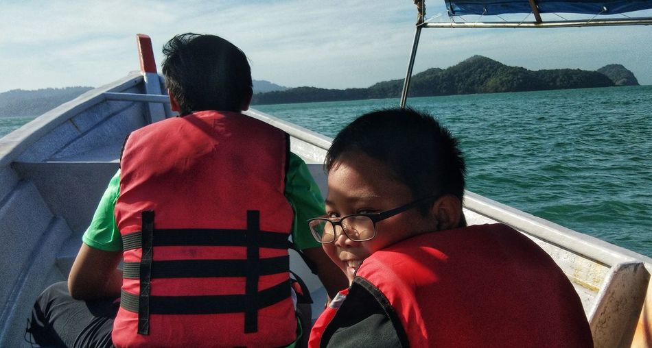 Rear view of people sitting on boat against sea