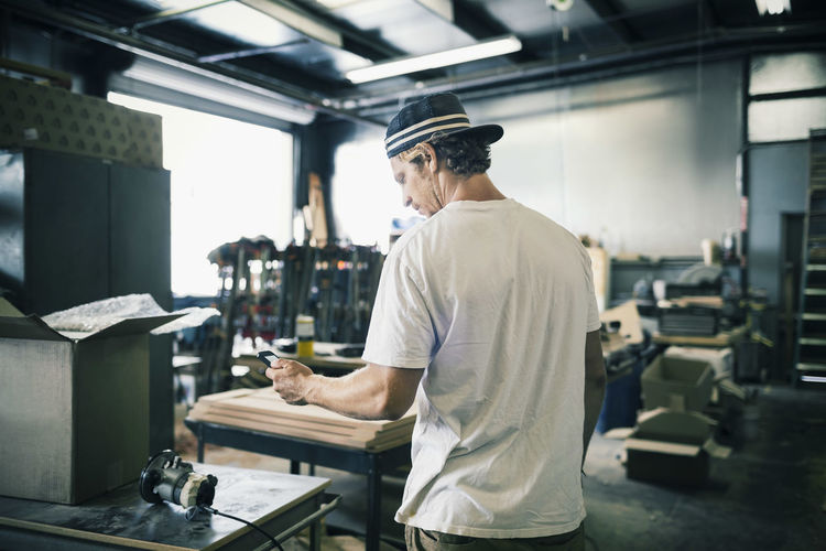 Carpenter using mobile phone in workshop