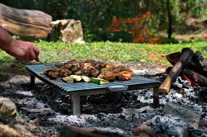 Grilling various meat and vegetables on flame