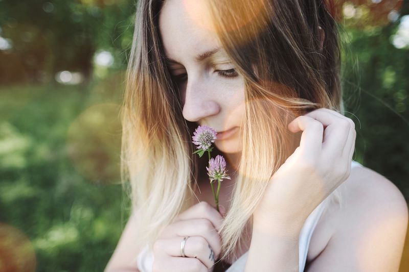 Close-up of blond woman smelling flowers