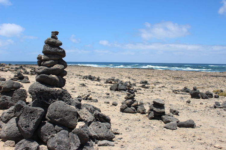 Stack of pebbles on beach against sky