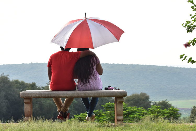 Rear view of couple sitting in rain