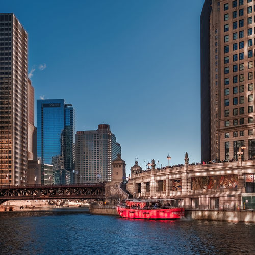 Buildings by river against clear sky