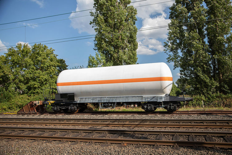 White fuel tank transportation container with orange line on siding of railway