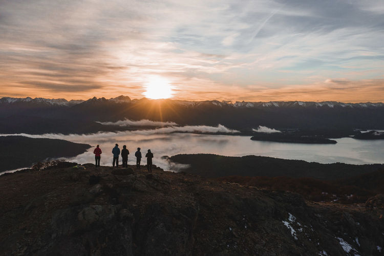 People standing on mountain against sky during sunset