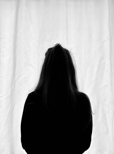 Rear view of woman standing against curtain