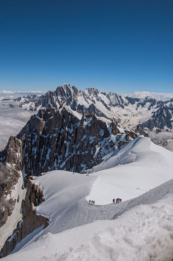 Snowy peaks and mountaineers in a sunny day at the aiguille du midi, near chamonix, france.