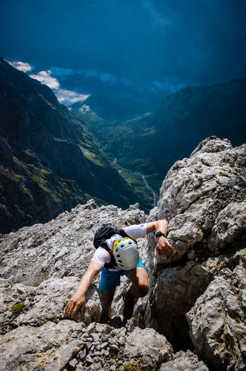 Full length of man climbing rocky mountain on sunny day