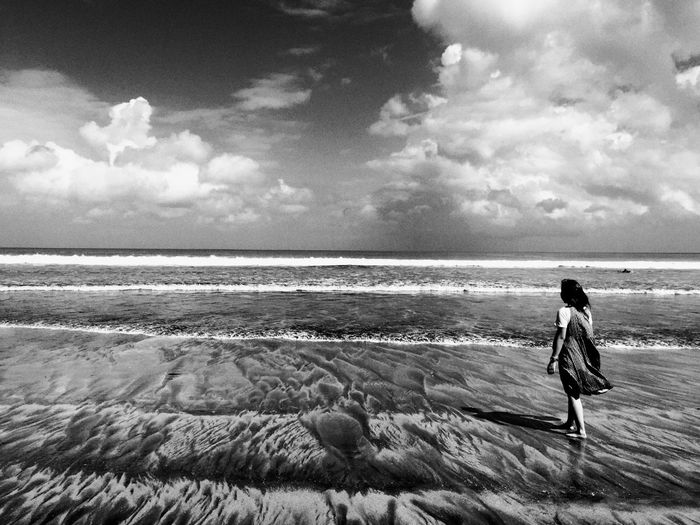 Woman standing on beach against sky