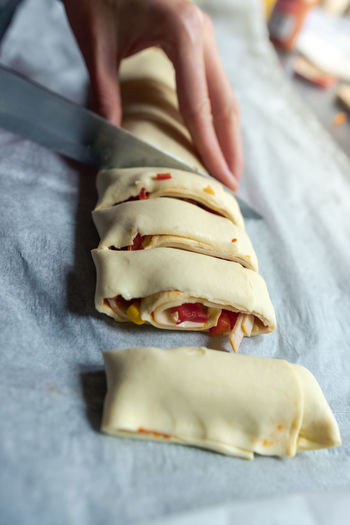 Female hands cut the rolled puff pastry into equal pieces. 