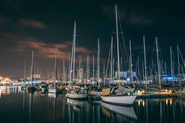 Sailboats moored in harbor at night