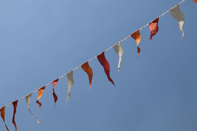 Low angle view of buntings hanging against clear blue sky