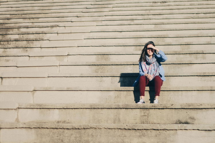 Woman shielding eyes while sitting on steps