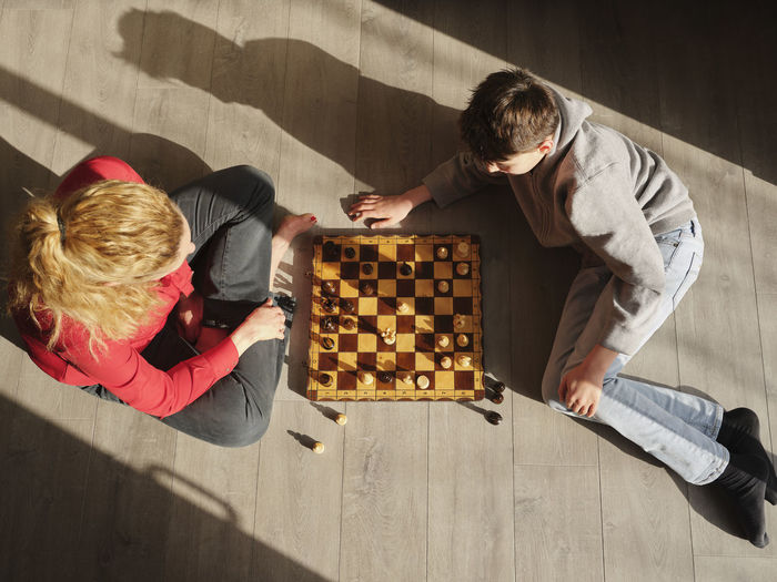 Mature woman playing chess with son at home